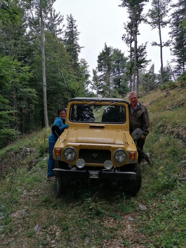 Zwei Menschen stehen links und rechts neben einem alten Jeep Baujahr 1979